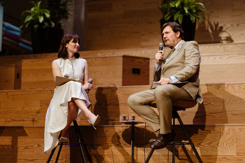 Chief Justice Wagner speaks into a microphone while sitting on stage with a moderator
