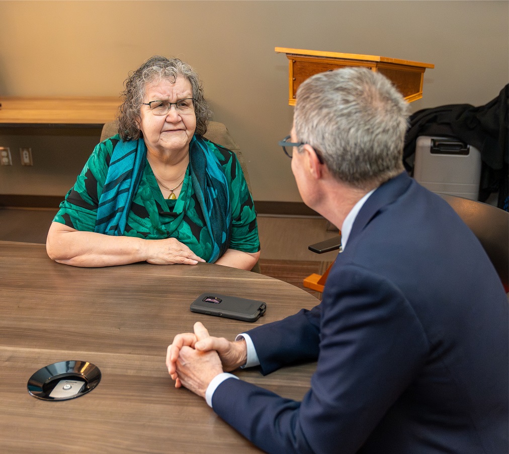 Justice Kasirer speaks to an Elder at a table