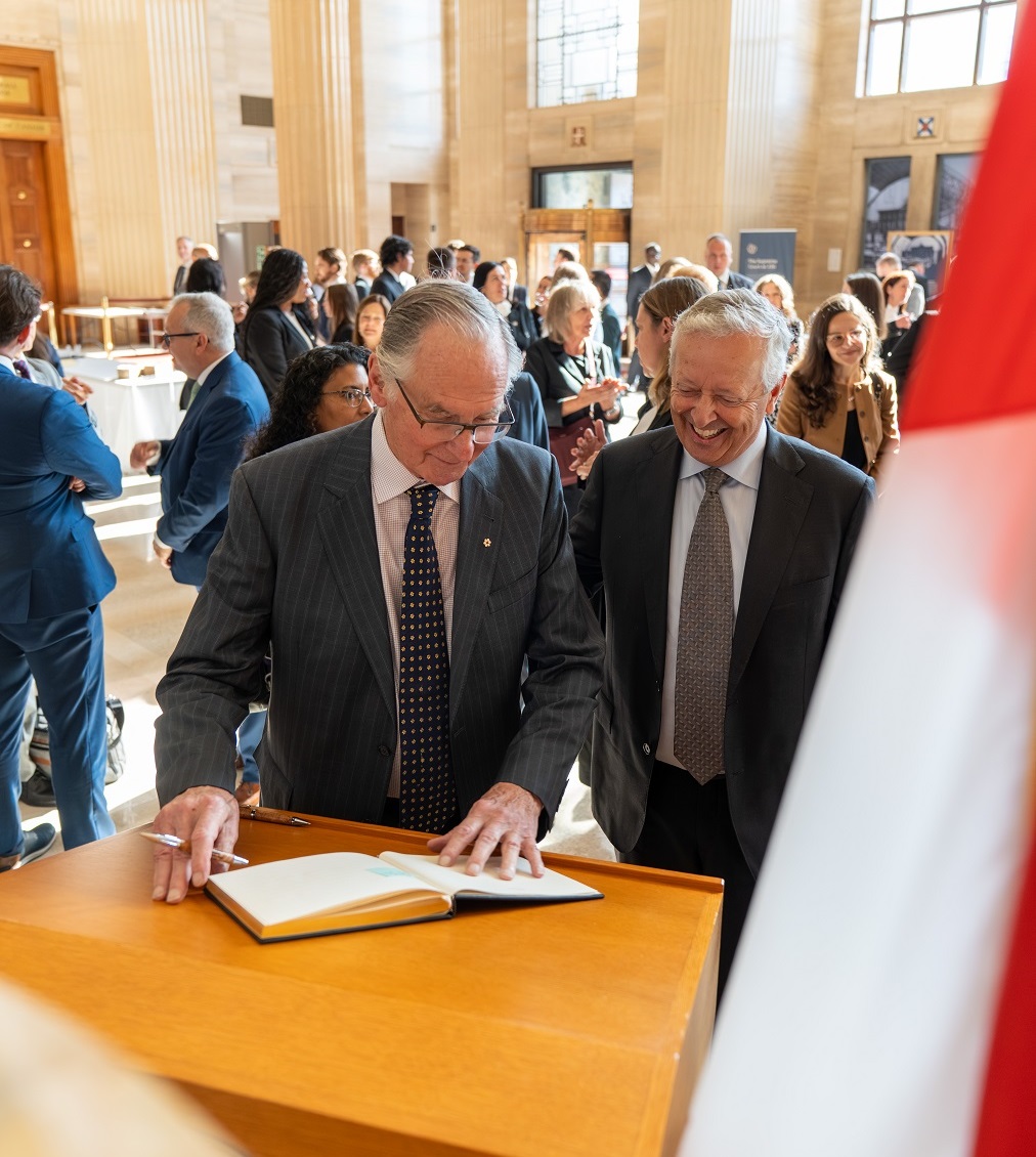 2 guests sign a guest book in the grand entrance hall of the Supreme Court