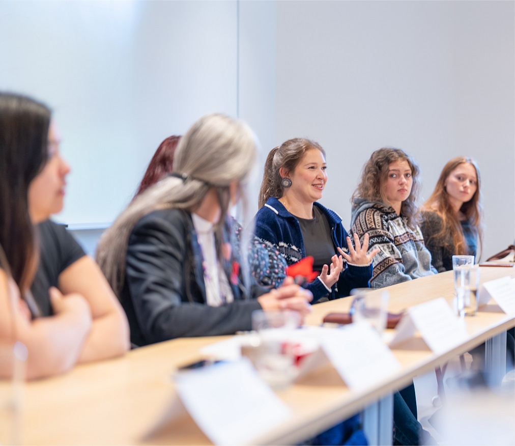 Students and faculty speaking at a meeting table
