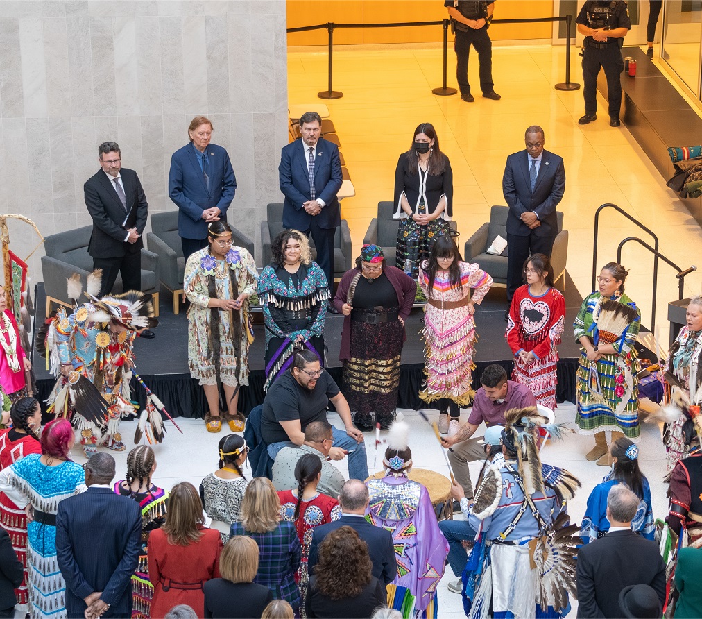 The judges watch from a stage while Indigenous drummers and dancers perform