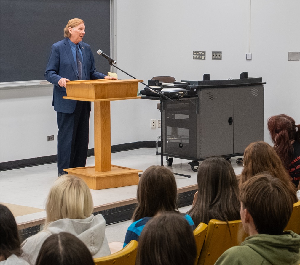 Justice Rowe speaks to students at a podium in a classroom