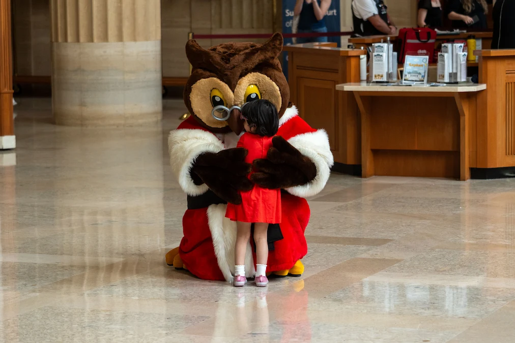 Amicus, the Court’s mascot, hugs a small child in the grand entrance hall